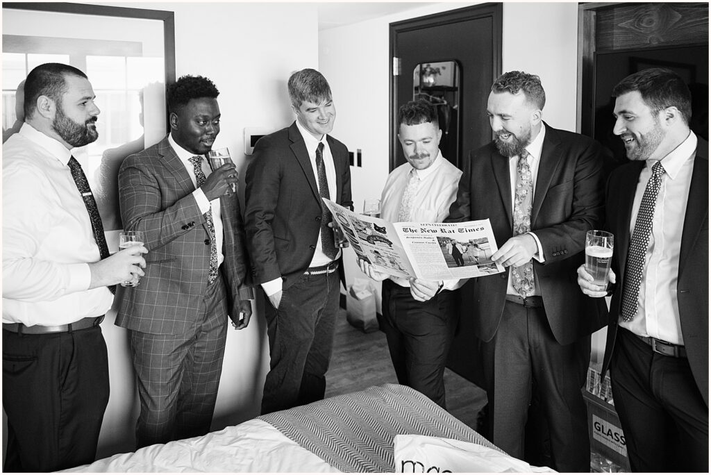 A groom and his groomsmen read a wedding newspaper.
