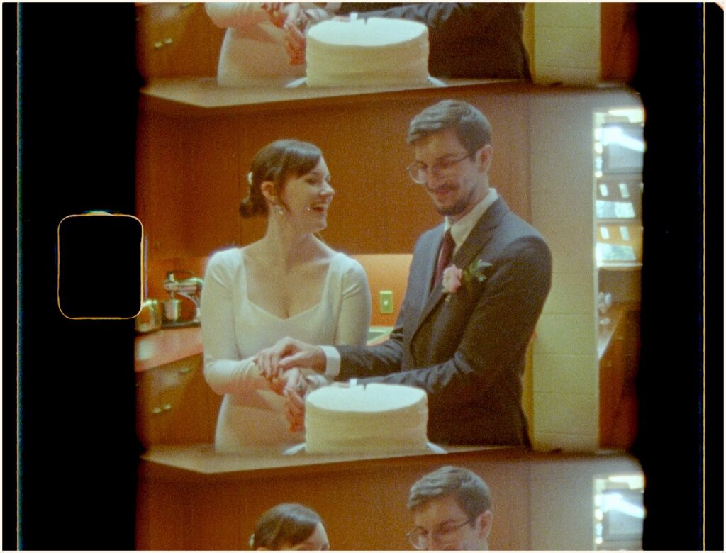 A bride and groom cut a wedding cake in a still from a Super 8 wedding video.