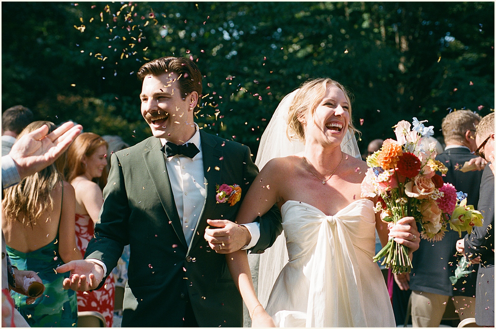 A bride and groom laugh during their recessional in film wedding photography.