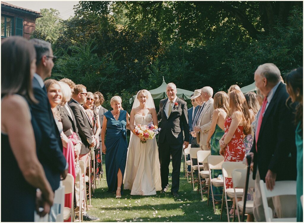 A bride's father walks her up the aisle an outdoor wedding in Portland.