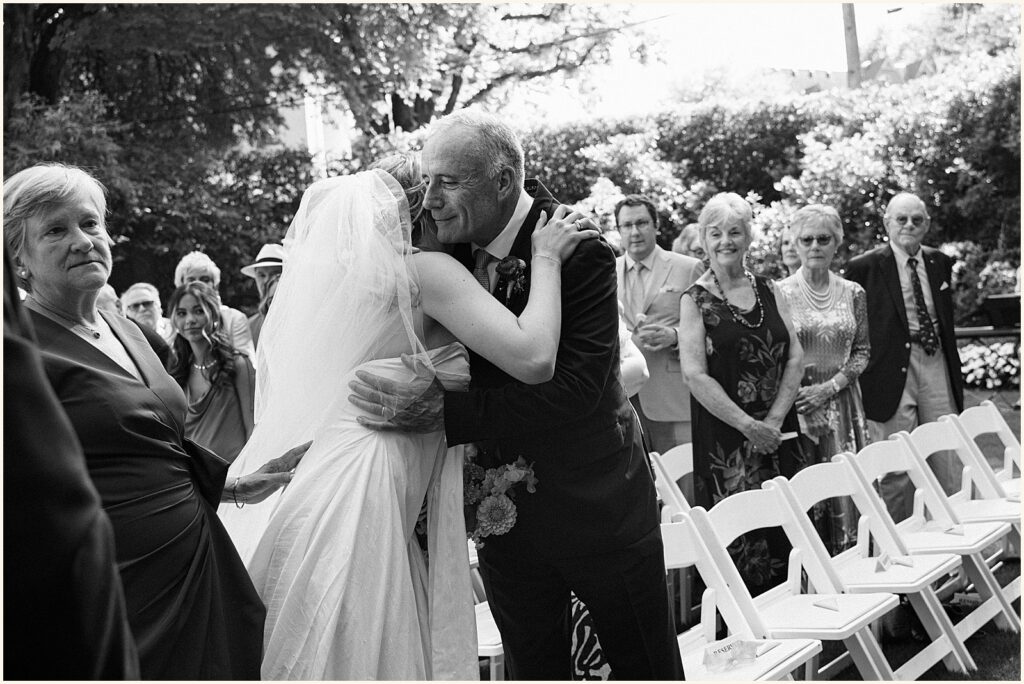 A bride's father hugs her at a Portland wedding ceremony.