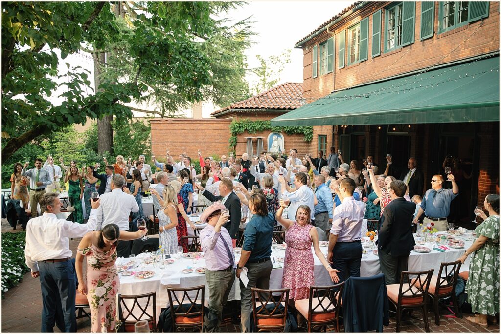 Wedding guests raise their glasses at a wedding reception photographed on film.